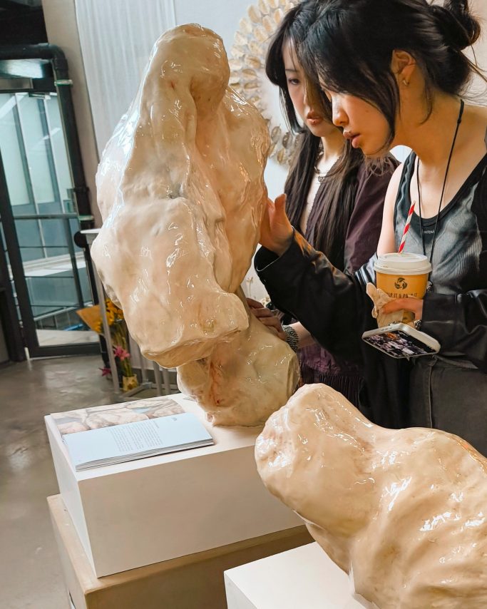 visitors looking intently and touching 'the hero' statue